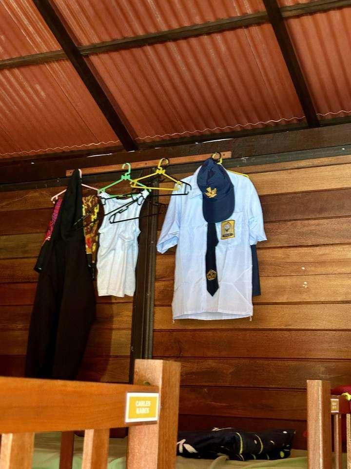 Schuluniform mit Mütze und Krawatte hängt an der Holzwand
