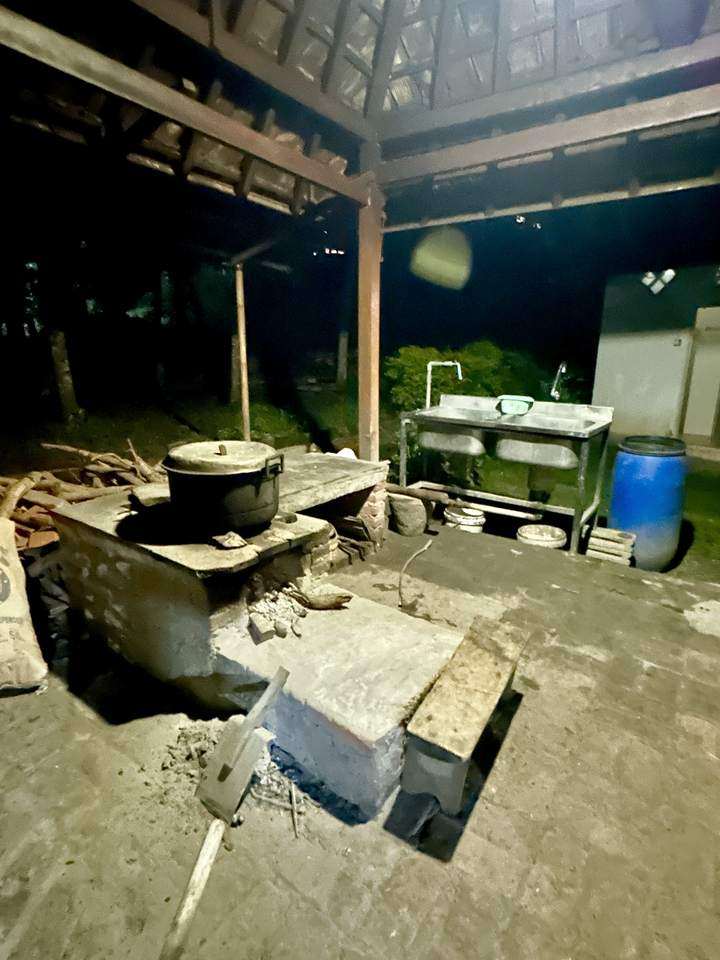 Außenküche mit einem Topf auf einer Feuerstelle und einer Spüle