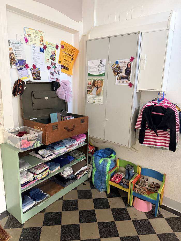 Kleiderregal und alter Koffer mit Kindersachen in der Kinderarztpraxis